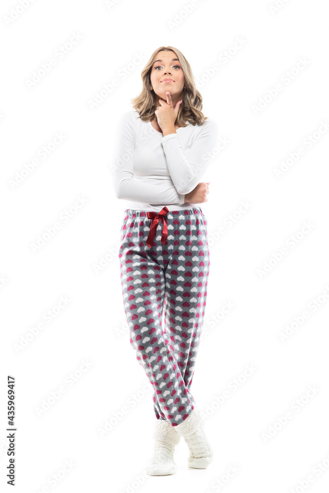 Cute curious and interested young woman in pajamas with finger on chin and asking expression. Full body length isolated on white background. Cute curious and interested young woman in pajamas with finger on chin and asking expression. Full body length isolated on white background.