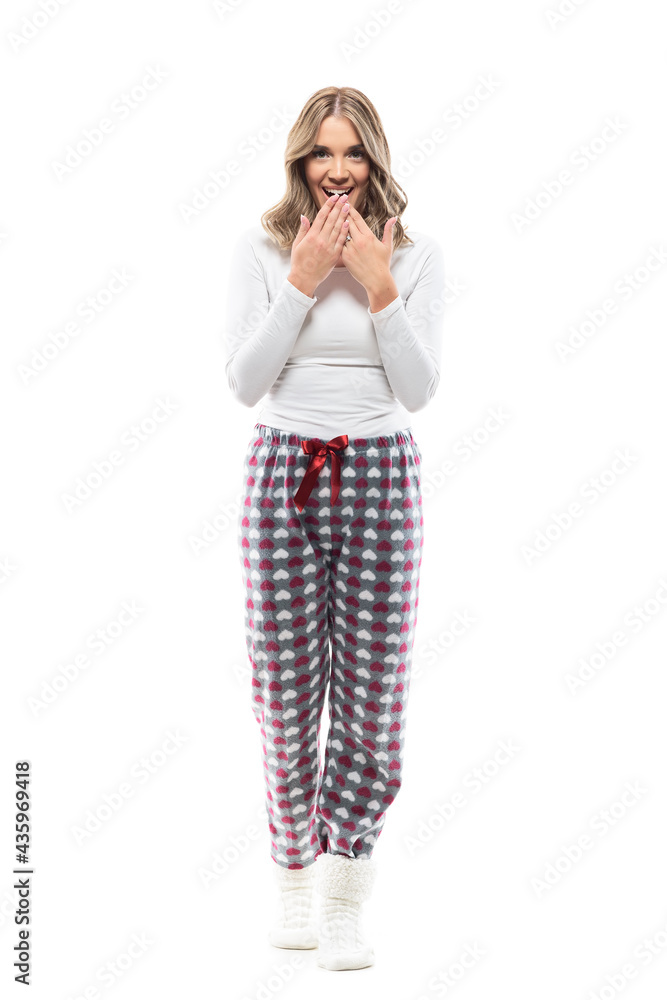 Fascinated and amazed young woman in comfy pajama with surprised covering mouth expression. Full body length isolated on white background. Fascinated and amazed young woman in comfy pajama with surprised covering mouth expression. Full body length isolated on white background.