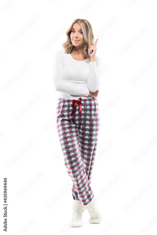 Cute young woman in comfy pajama looking at camera having idea with finger pointed up. Full body length isolated on white background. Cute young woman in comfy pajama looking at camera having idea with finger pointed up. Full body length isolated on white background.