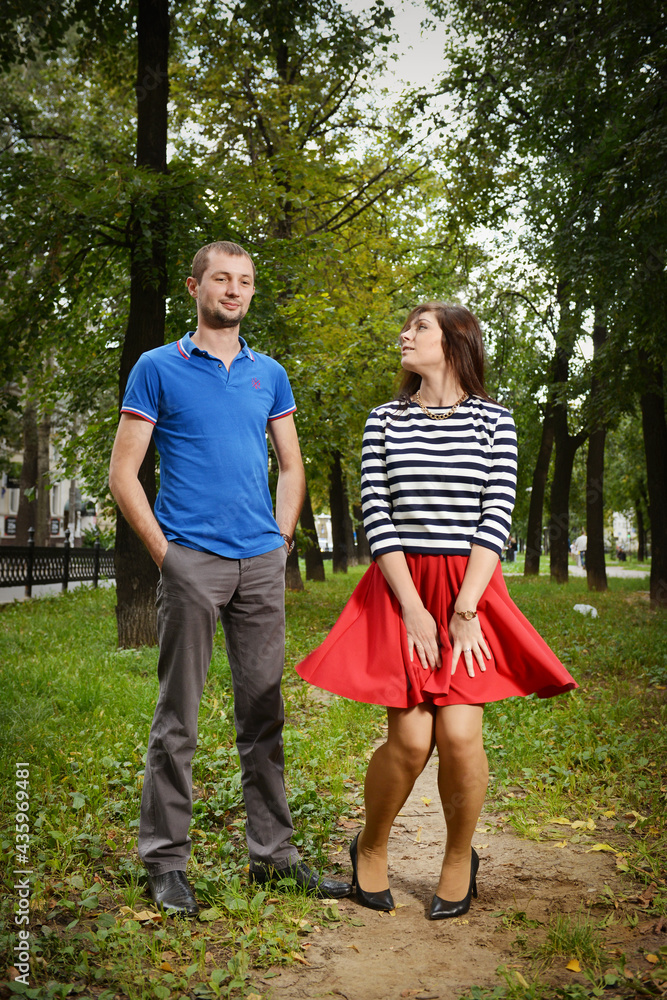 Obraz premium The girl coquettishly holds the edge of the red dress.
