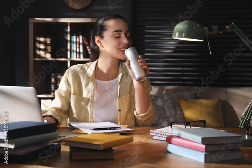 Young woman with energy drink studying at home