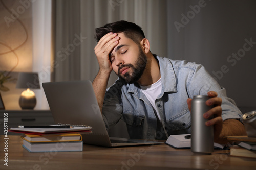 Photography Tired young man with energy drink studying at home