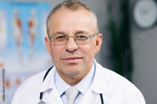 Portrait of Caucasian Family Medical Doctor in Glasses is in Health Clinic. Successful Physician in White Lab Coat Looks at the Camera and Smiles in Hospital Office