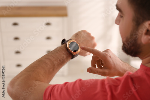 Young man using smart watch at home, closeup