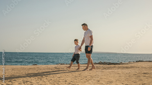 Father and  son  spending time together sea vacation. Young man, little boy walking beach Fathers day. Family with one child. Happy childhood with daddy.