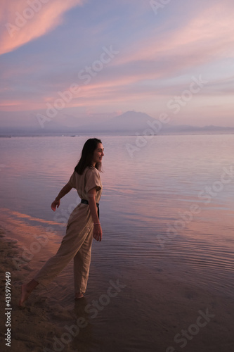 Young girl posing on the beach against the background of a volcano.