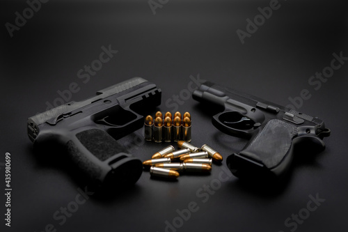 Fotomurale Short pistol with ammunition placed on a dark black background.