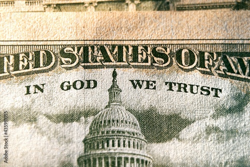 A macro close up photo emphasizing the inscription In God We Trust printed on the back of a United States ten dollar bill with selective focus on the words In God We Trust. photo