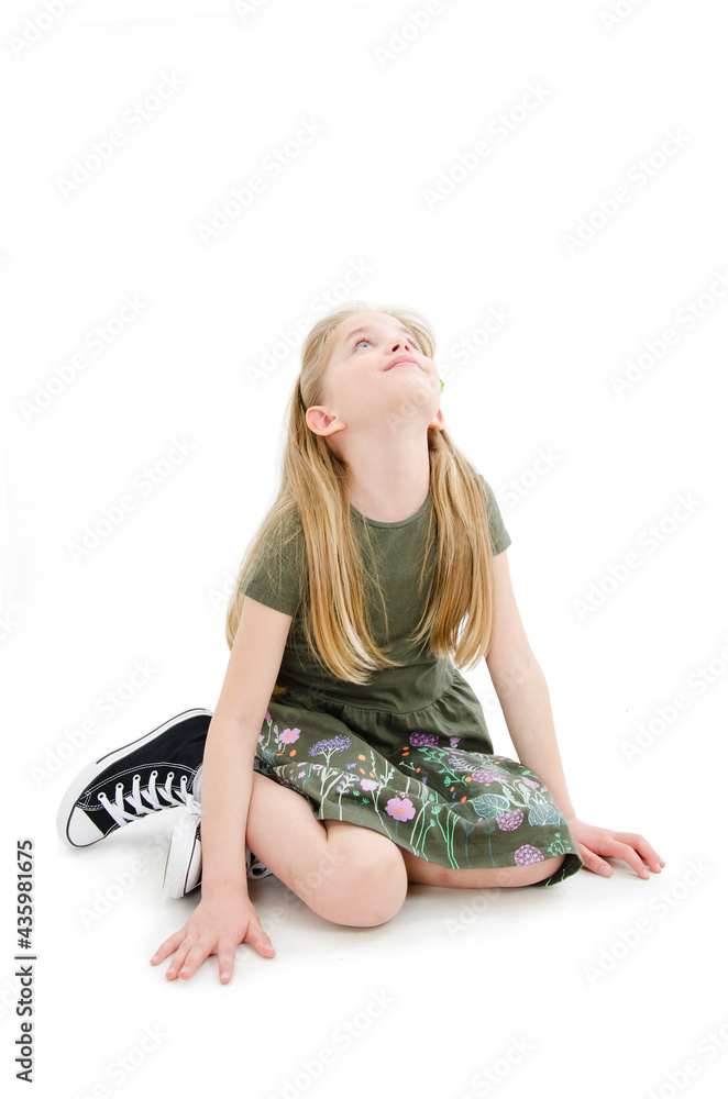 Portrait of a cute girl sitting on the knees, looking up on copy space