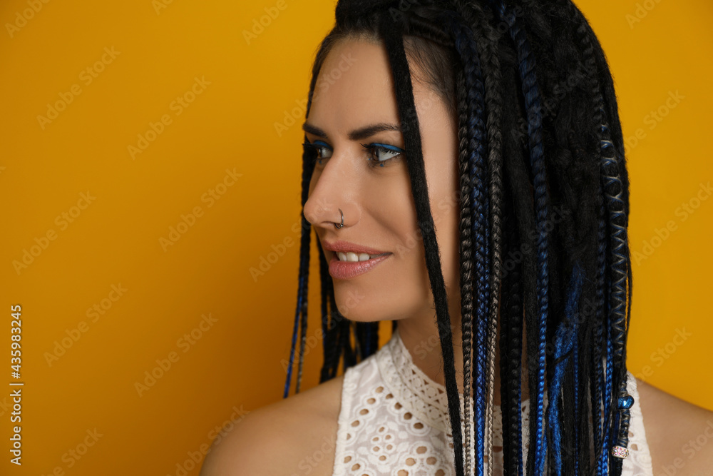 Beautiful young woman with nose piercing and dreadlocks on yellow background. Space for text