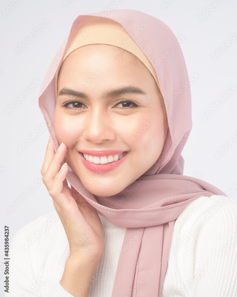 Portrait of young smiling muslim woman wearing a pink hijab over white background studio. Portrait of young smiling muslim woman wearing a pink hijab over white background studio.