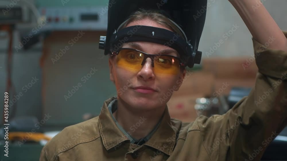 The female welder takes off her mask and smiles The female welder takes off her mask and smiles