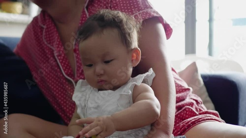 Cute Asian baby girl concentrating as she plays with a cuddly toy. photo