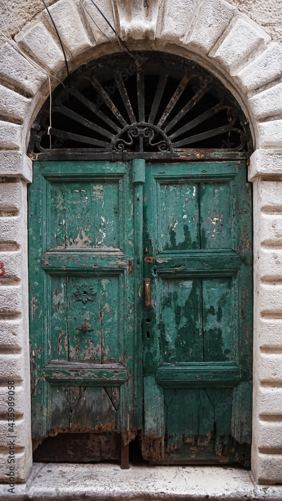 an old wooden green door with a metal canopy above it, in Kotor, Montenegro