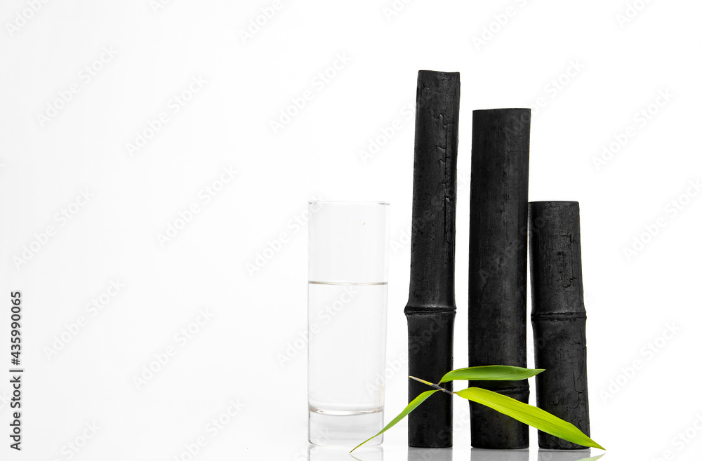 Bamboo charcoal water filter sticks, green leaf and glass of water. Natural bamboo charcoal is a powerful purifier which refreshes tap water