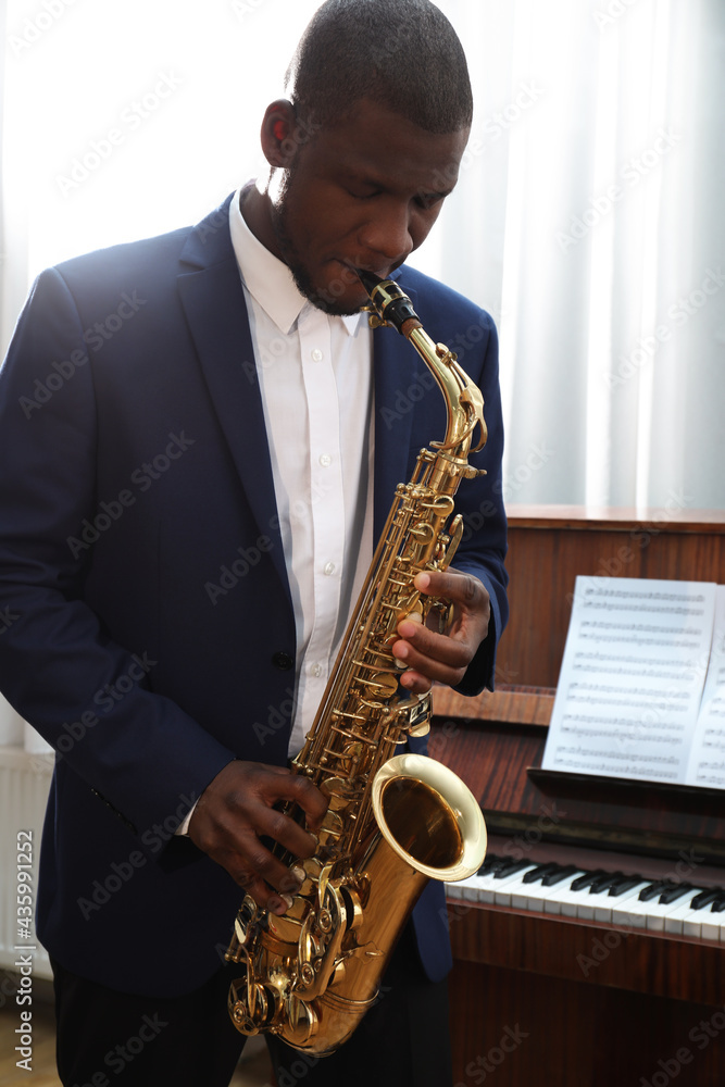 Fototapeta premium African-American man playing saxophone indoors. Talented musician