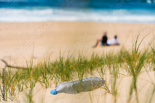 plastic bottle polluting the beach with tourists in the background photo