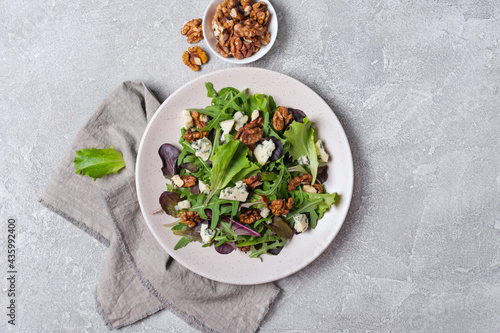 Healthy vegetarian salad with mix of fresh green leaves, blue cheese and walnuts