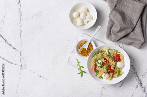 Pasta with cherry tomatoes, soft cheese, mustard sauce and arugula leaves