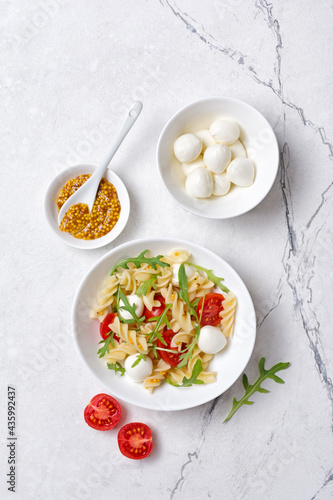 Pasta with cherry tomatoes, soft cheese, mustard sauce and arugula leaves