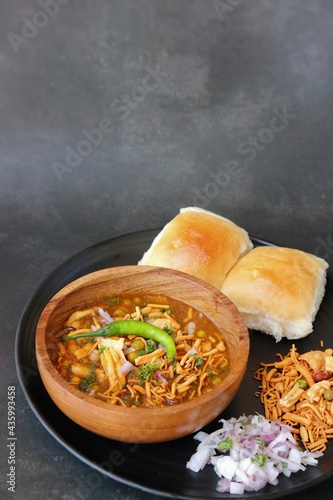 Spicy Misal Pav or usal Pav is a traditional snack or Chaat food from Maharashtra, India. Served with chopped onion, lemon wedges and farsan. Selective focus with copy space