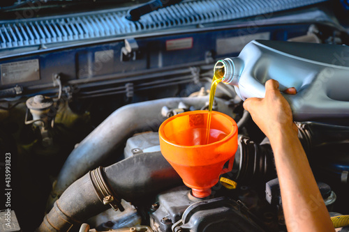 Car mechanic working in a car repair shop Pour the engine oil to change the engine oil in the garage for customers who use it Car repair and oil change