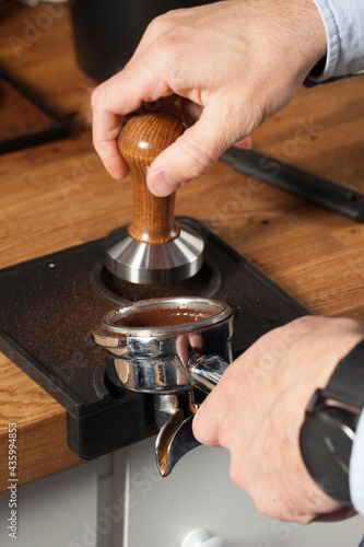 Barista pressing fresh coffee grounds in a cafe, selective focus