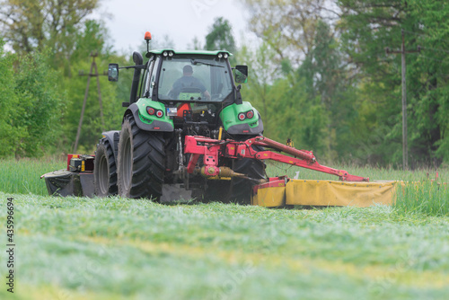 Koszenie trawy przy użyciu ciągniętej przez traktor kosiarki rotacyjnej.