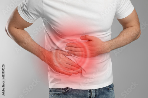 Man suffering from pain in lower right abdomen on light grey background, closeup. Acute appendicitis photo