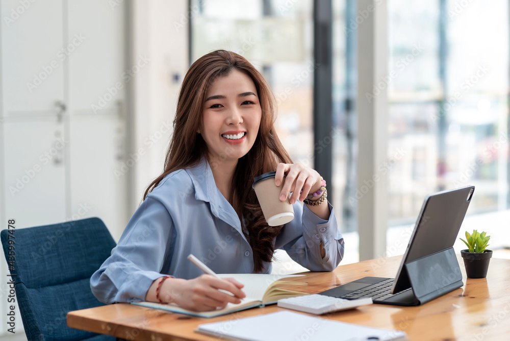 Charming Asian businesswoman drinking coffee ready to work at the office. Looking at camera. Charming Asian businesswoman drinking coffee ready to work at the office. Looking at camera.
