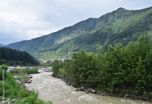 A picture of the beautiful Beas river flowing through the Himalayan mountains in Manali, cutting through forests and rocks.