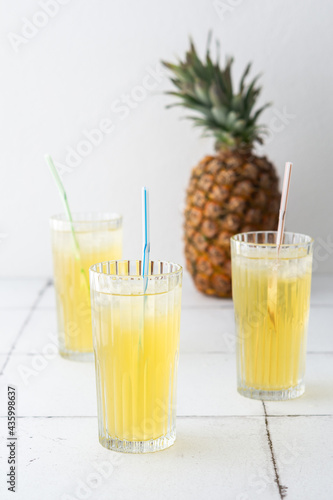Delicious sweet refreshing pineapple juice with ice in glasses with a straw