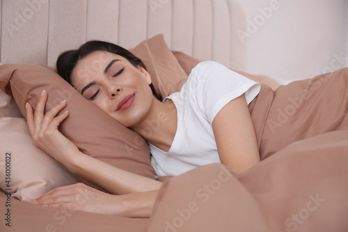 Woman sleeping in comfortable bed with beige linens