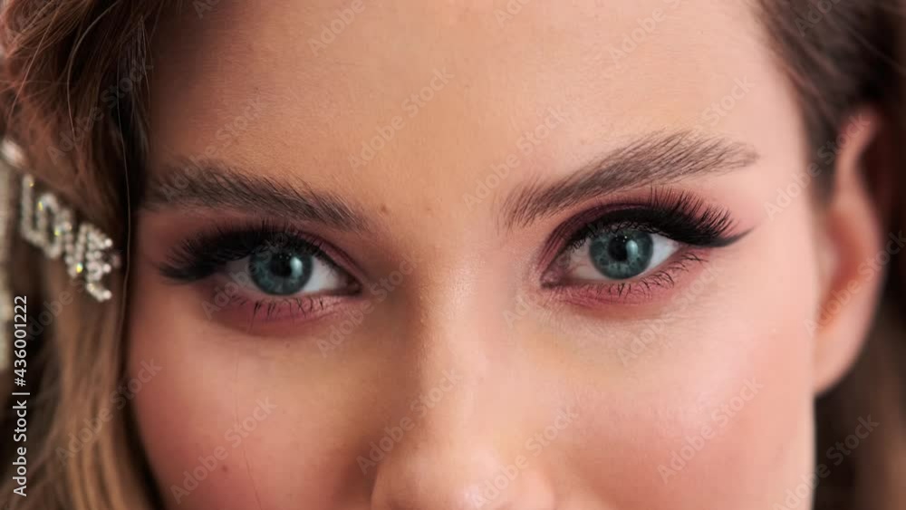A close-up cropped view of a positive young woman wearing gorgeous jewelries and hairpins is looking to the camera standing isolated over a pink wall in the studio A close-up cropped view of a positive young woman wearing gorgeous jewelries and hairpins is looking to the camera standing isolated over a pink wall in the studio
