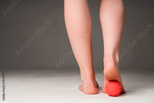 Obraz na plátně Photo of female legs kneading feet with a massage ball and doing exercises with