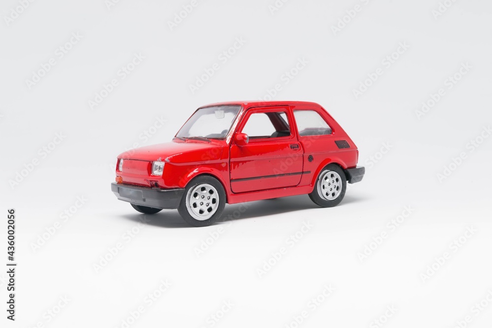 Maluch samochód zabawka koloru czerwonego stojący bokiem na białym tle  - obrazy, fototapety, plakaty 