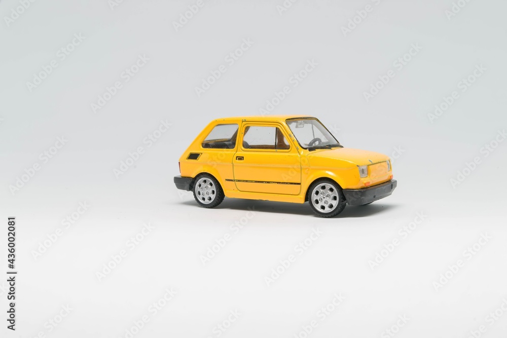 Obraz na płótnie Maluch samochód zabawka koloru żółtego stojący bokiem na białym tle w salonie