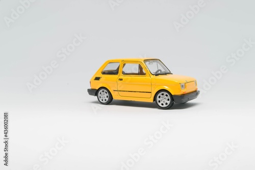 Maluch samochód zabawka koloru żółtego stojący bokiem na białym tle