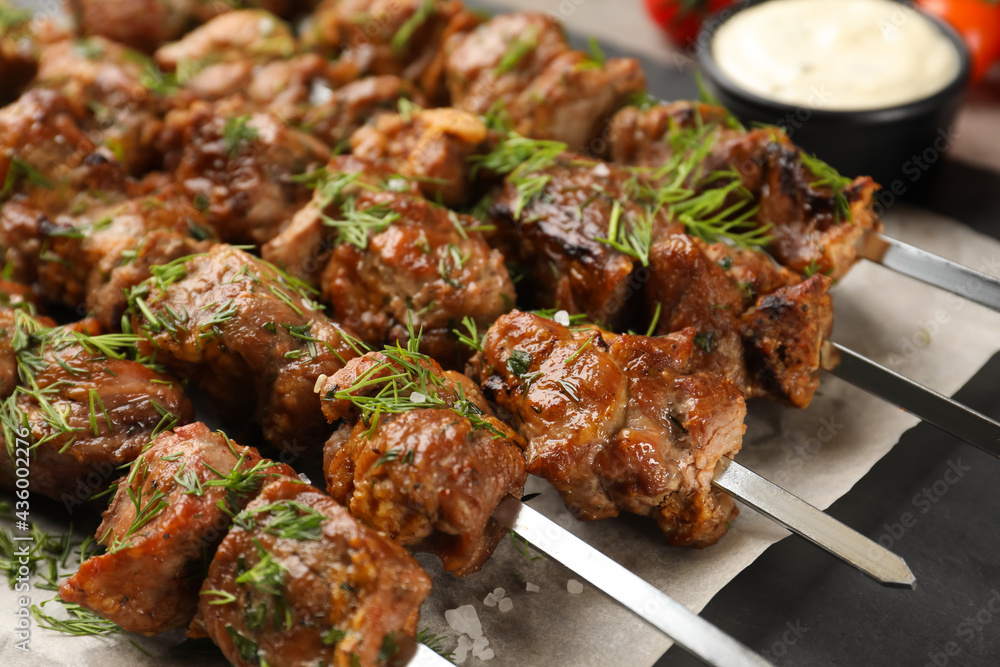 Metal skewers with delicious meat on table, closeup