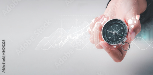 Business navigate concept, Businessman holding compass navigation for guide to recovery business planning growth in the economic crisis and trading graph financial data, action plan icon. photo
