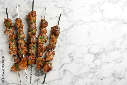 Konstfotografi Metal skewers with delicious meat on white marble table, flat lay