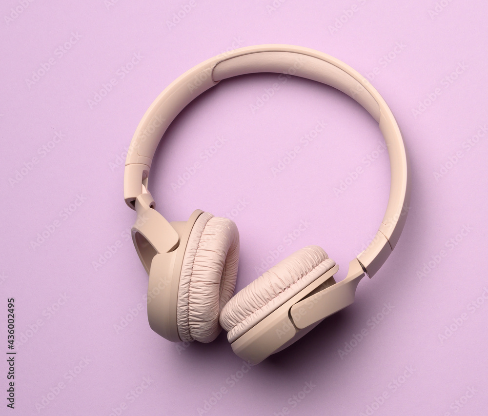 beige wireless headphones on a purple background beige wireless headphones on a purple background
