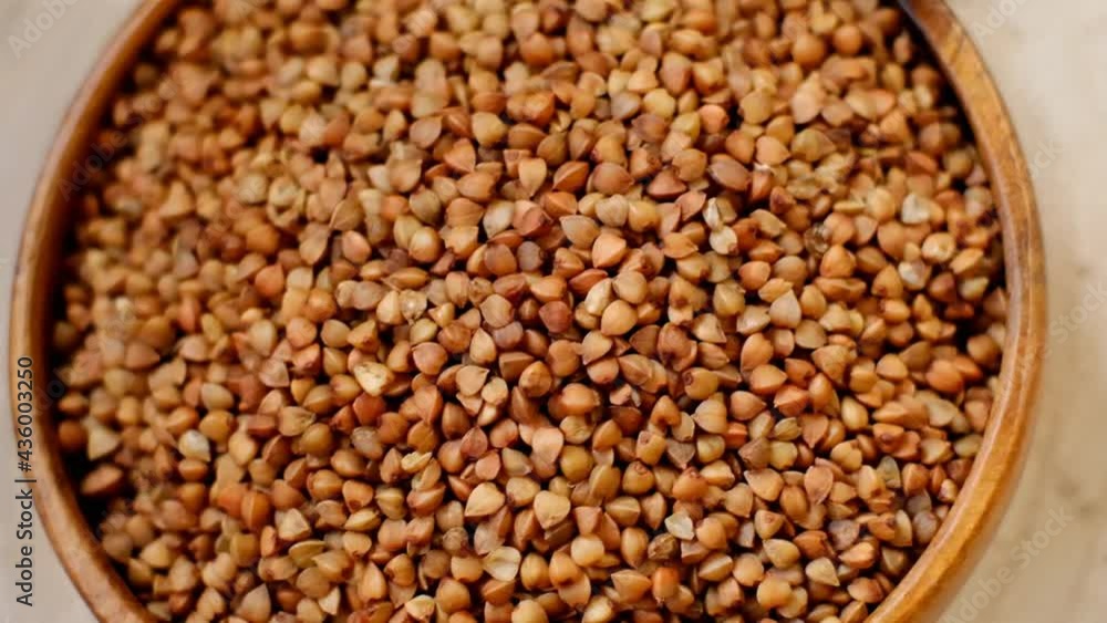 Buckwheat grain in a round wooden cup.Brown buckwheat grain texture Buckwheat grain in a round wooden cup.Brown buckwheat grain texture