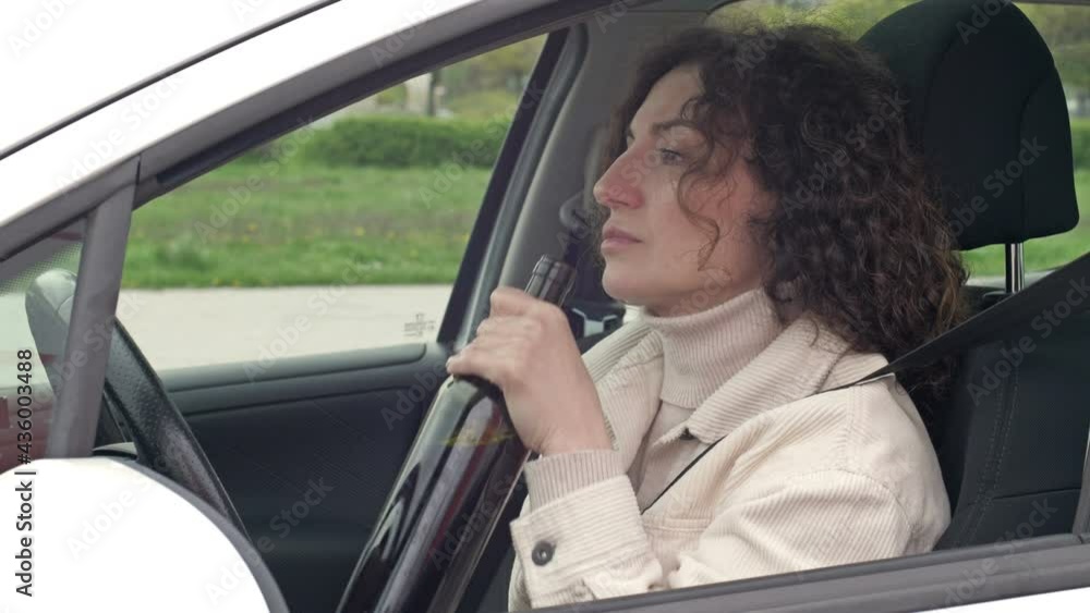 Woman is drinking wine while sitting in her car. Woman is drinking wine while sitting in her car.
