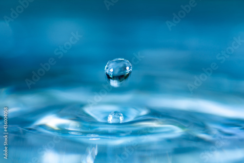 water drop splash in a glass blue colored shot of water that is dripping and reflecting water.