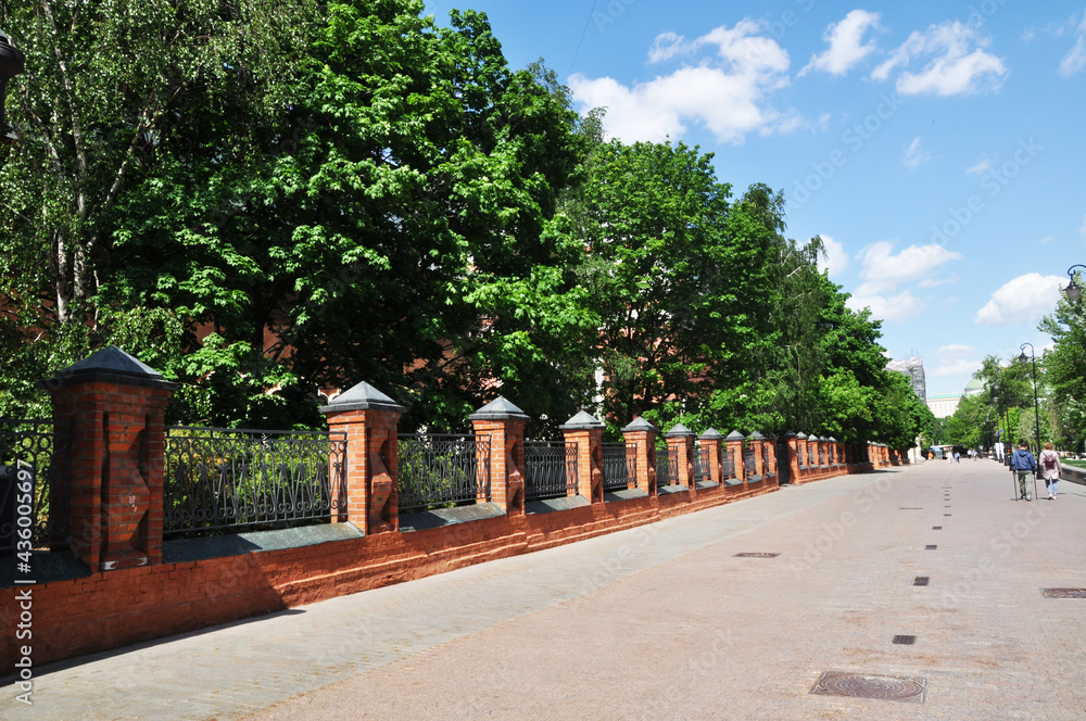 Street view in the old district of Moscow. Red brick fence with metal bars.