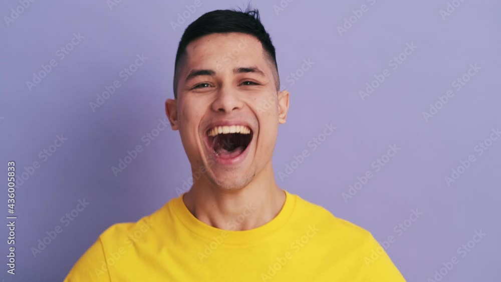 The positively surprised man screaming and making a winner gesture while standing in the purple studio The positively surprised man screaming and making a winner gesture while standing in the purple studio