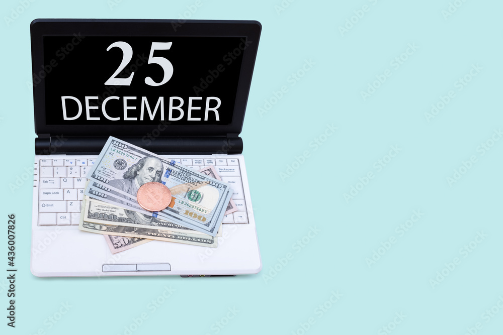 Laptop with the date of 25 december and cryptocurrency Bitcoin, dollars on a blue background. Buy or sell cryptocurrency. Stock market concept.