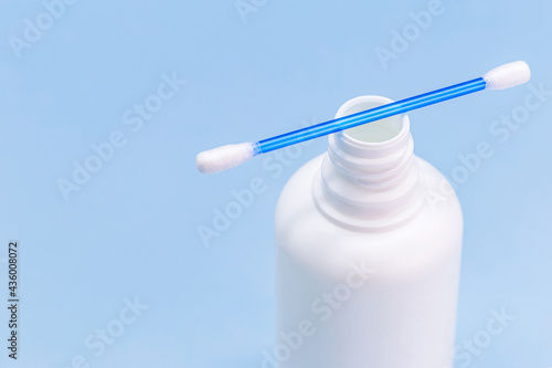 hydrogen peroxide, in white plastic bottle, with cotton swab and isolated blue background, medicine concept, medicine for wounds and small cuts photo