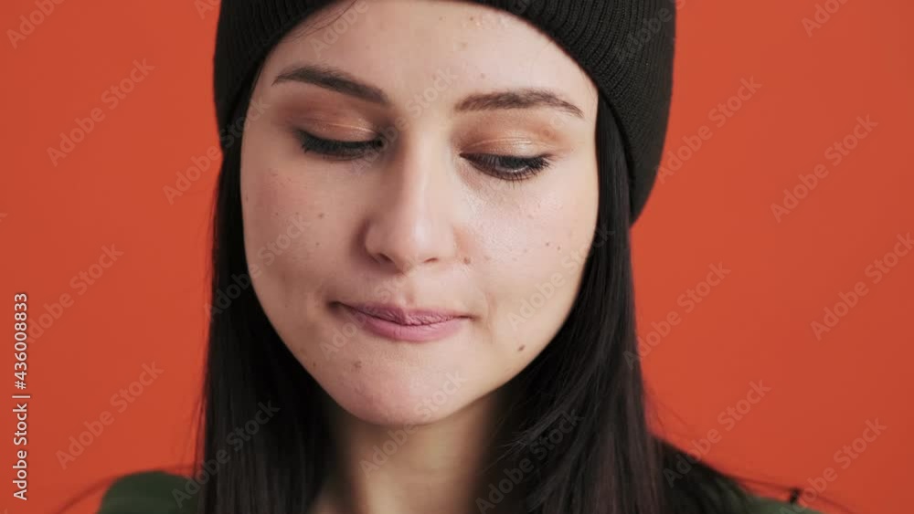 A close-up view of a thinking woman is looking to the side standing isolated over red wall in the studio A close-up view of a thinking woman is looking to the side standing isolated over red wall in the studio